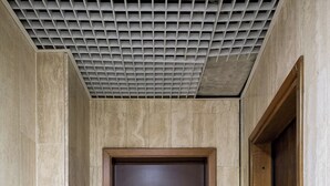 Un couloir avec une porte en bois et un interrupteur fixé au mur.