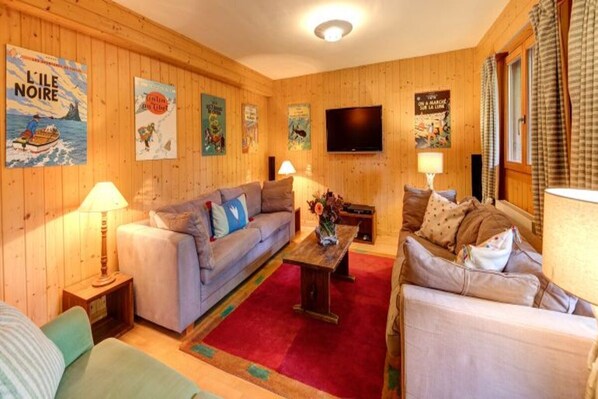 Una habitación acogedora con paredes de madera, un sofá, una mesa de centro y un televisor.
