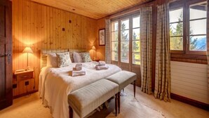 Un dormitorio con paneles de madera, una cama grande, lámparas de noche y vistas al exterior a través de una ventana.