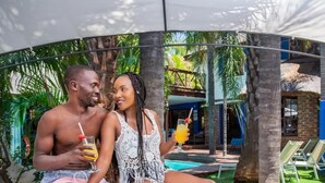 Un couple se détend au bord d’une piscine, avec la piscine et des chaises longues visibles en arrière-plan.