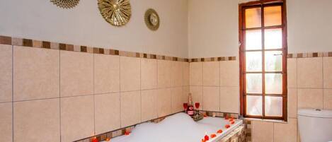 A bathroom with a bathtub, a toilet, and a window.
