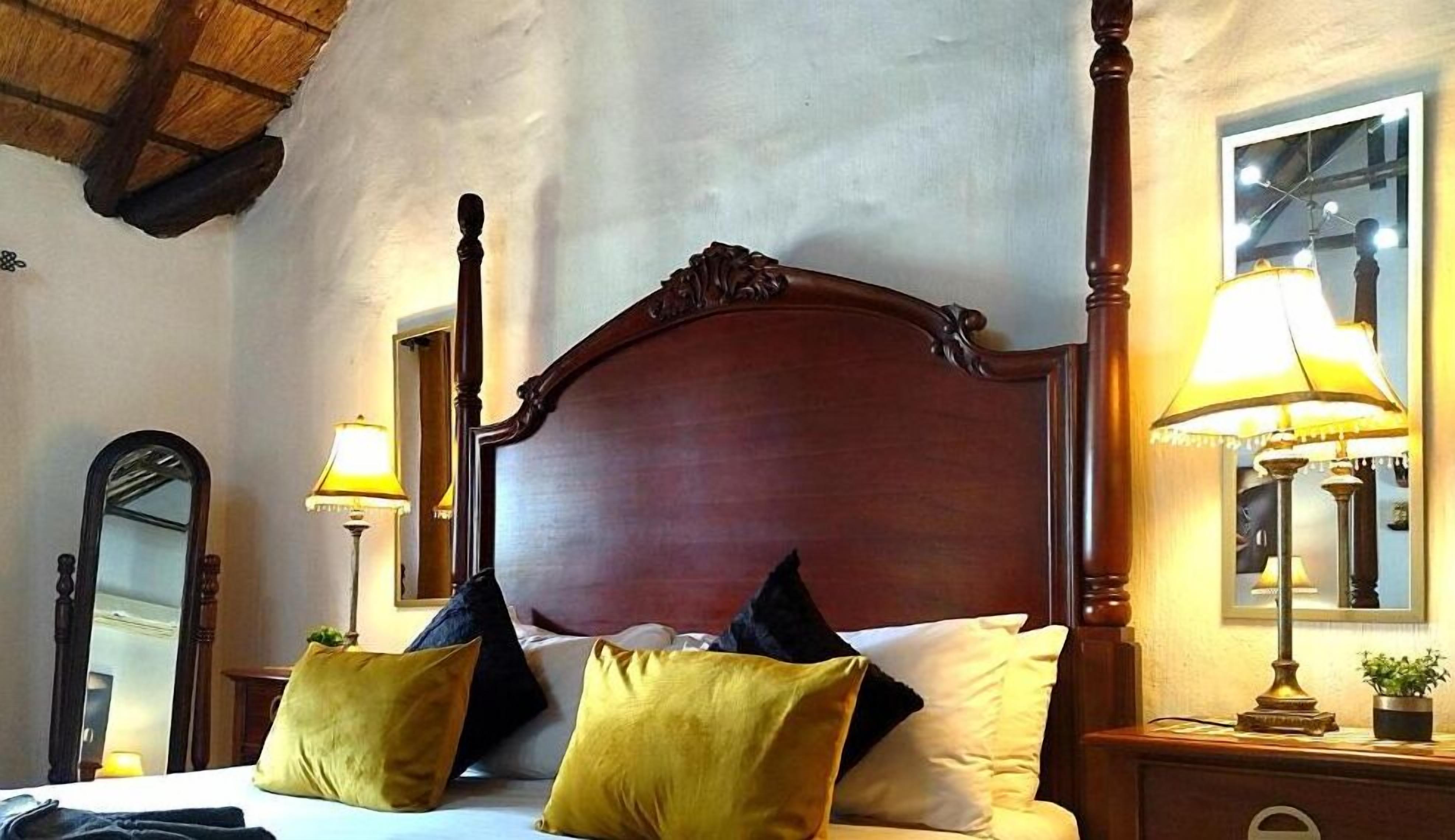 A bedroom with a wooden bed, two bedside lamps, a mirror, and a window with a view.