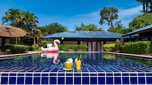 A swimming pool with a tiled edge, a pink flamingo float, and a coconut drink on the edge. - Satva (Koh Samui)
