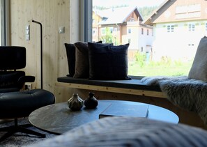 Relax in a stylish room with a comfortable seating area, sofa, and chair, plus a window offering a view of the surrounding buildings.