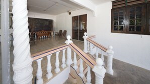 A staircase with white balustrades and a tiled floor leading to a room with a large window and a sofa. - OYO 90990 Sri Tempurung Homestay (Chukai)