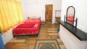 A bedroom with a bed, a ceiling fan, a wooden door, a mirror, and a patterned rug. - OYO 90990 Sri Tempurung Homestay (Chukai)