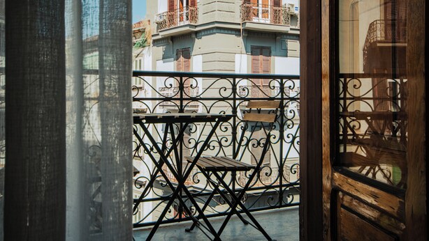 Een balkon met een sierhek van ijzer en een klein houten tafeltje.