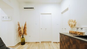 Een moderne keuken met een houten visgraatvloer, een witte deur en een klein eiland met een spoelbak en decoratieve objecten.