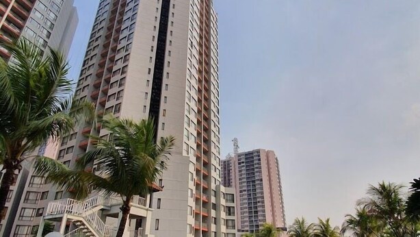 A swimming pool surrounded by tall residential buildings, palm trees, and a clear sky. - Apartemen Taman Rasuna 2BR. 80sqm (Jakarta)