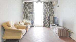 A living room with a sofa, a TV, and a wooden cabinet. - Apartemen Taman Rasuna 2BR. 80sqm (Jakarta)
