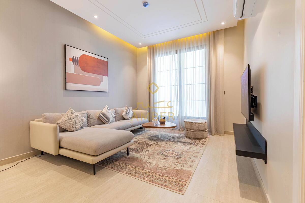 A modern living room with a sofa, a coffee table, a rug, and a TV mounted on the wall.