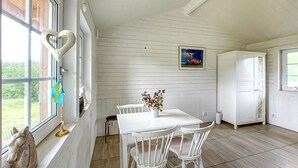 Ruokailutila, jossa on valkoinen pöytä ja tuolit, maljakko kukkineen, hevospatsas ja taulu seinällä.