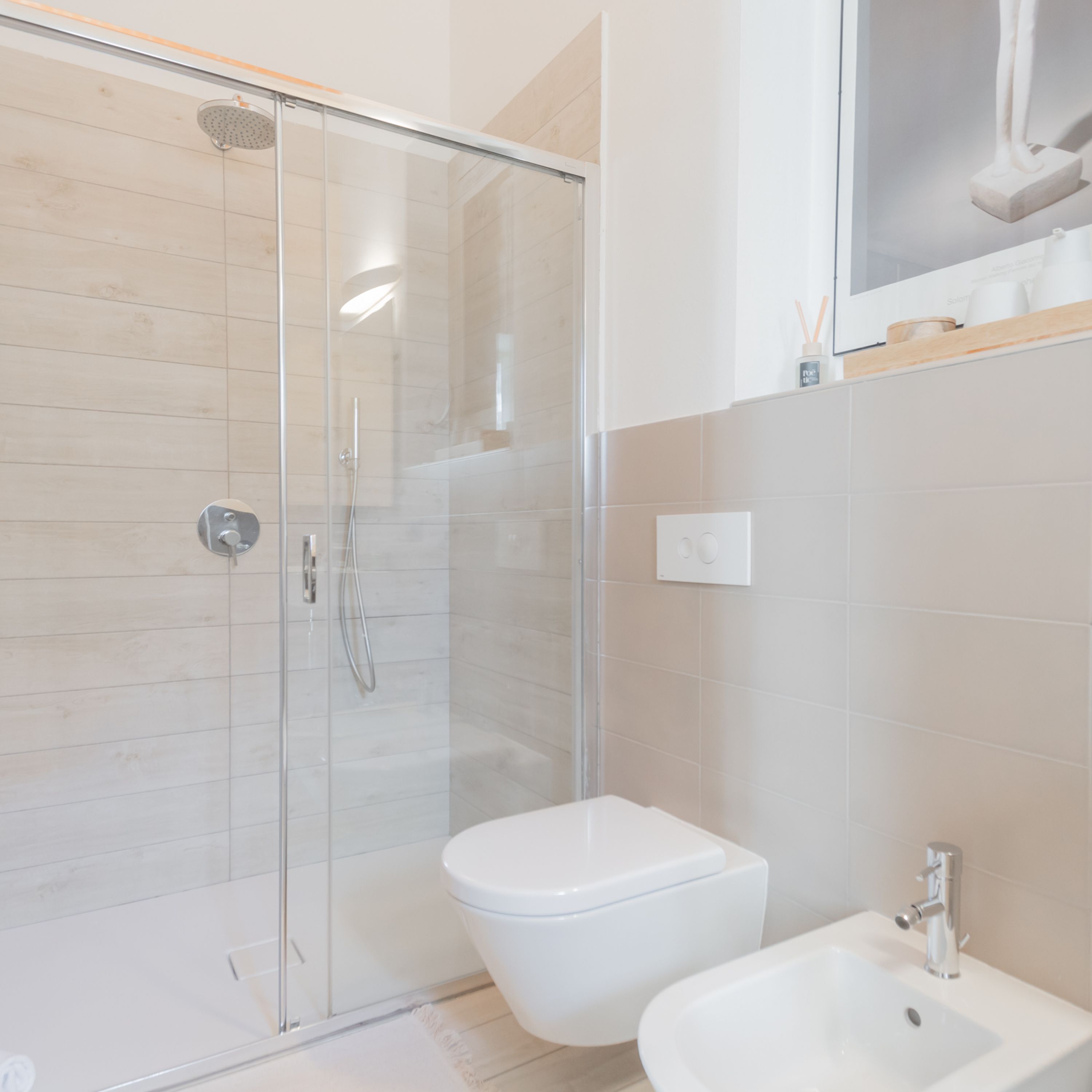 A modern bathroom with a glass-enclosed shower, a white toilet, and a sink with a chrome faucet.
