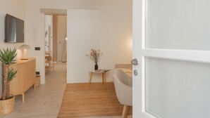 A modern interior with a high ceiling, a wooden floor, a white door, and a small table with a vase. - The Printers Home in Como (Como)
