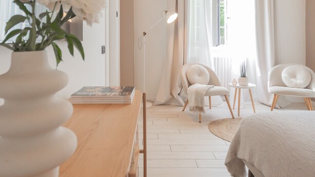 A modern bedroom with a wooden bed, two white chairs, a small table, and a floor lamp. - The Printers Home in Como (Como)