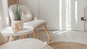 A minimalist room with a white sofa, a round table with a vase, a potted plant, and a woven rug. - The Printers Home in Como (Como)
