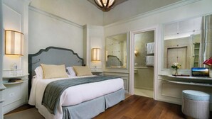 Une chambre à coucher avec un grand lit, des lampes de chevet, un miroir, une coiffeuse avec un miroir et un petit tabouret.