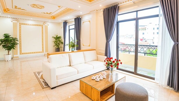 Amplia sala de estar con un sofá blanco, una mesa de centro de madera y un balcón con vistas.