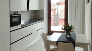 Et moderne køkken med hvide skabe, en sort bordplade og et spisebord med stole.