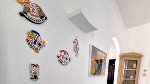 A living room with a blue sofa, decorative wall art, and a blue vase. - Casa FeFe a scenic view of Positano and a swimming pool! (Positano)
