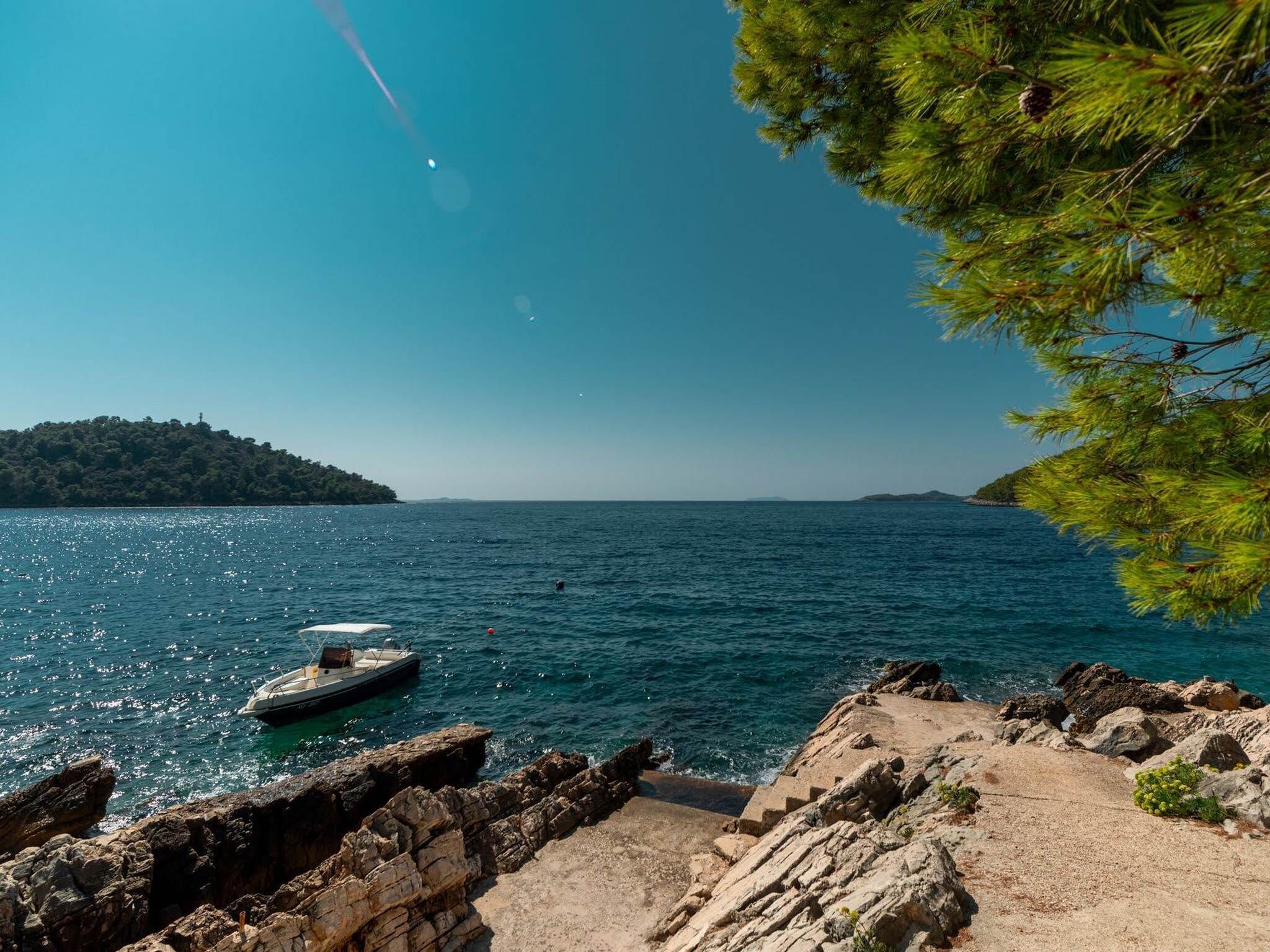 Une côte rocheuse avec un bateau ancré près du rivage.