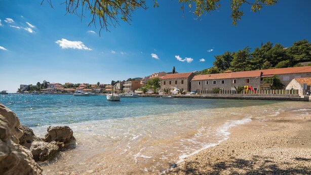 A coastal town with clear waters, a pebbly beach, and stone buildings with red roofs. - Fancy Apartments Dream (Smokvica)