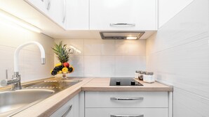 A modern kitchen with white cabinets, a stainless steel sink, and a fruit bowl on the counter. - Fancy Apartments Dream (Smokvica)