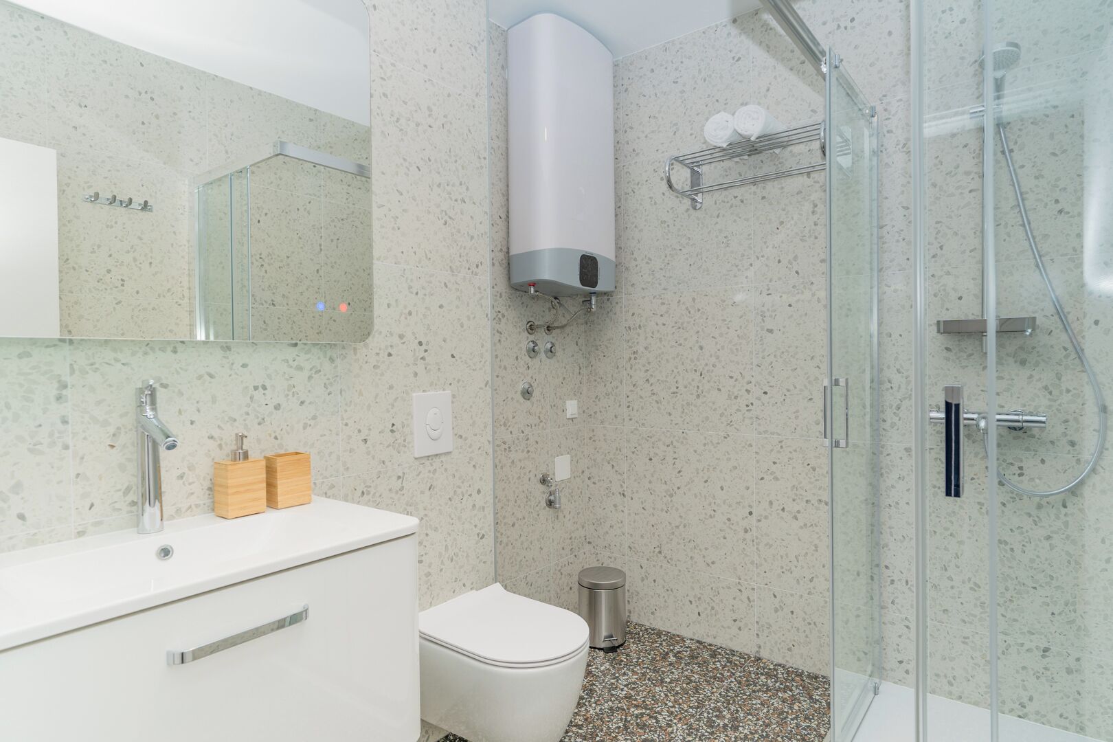 Ein Badezimmer mit Duschkabine aus Glas, einer weißen Toilette und einem Waschbecken mit Spiegel darüber.