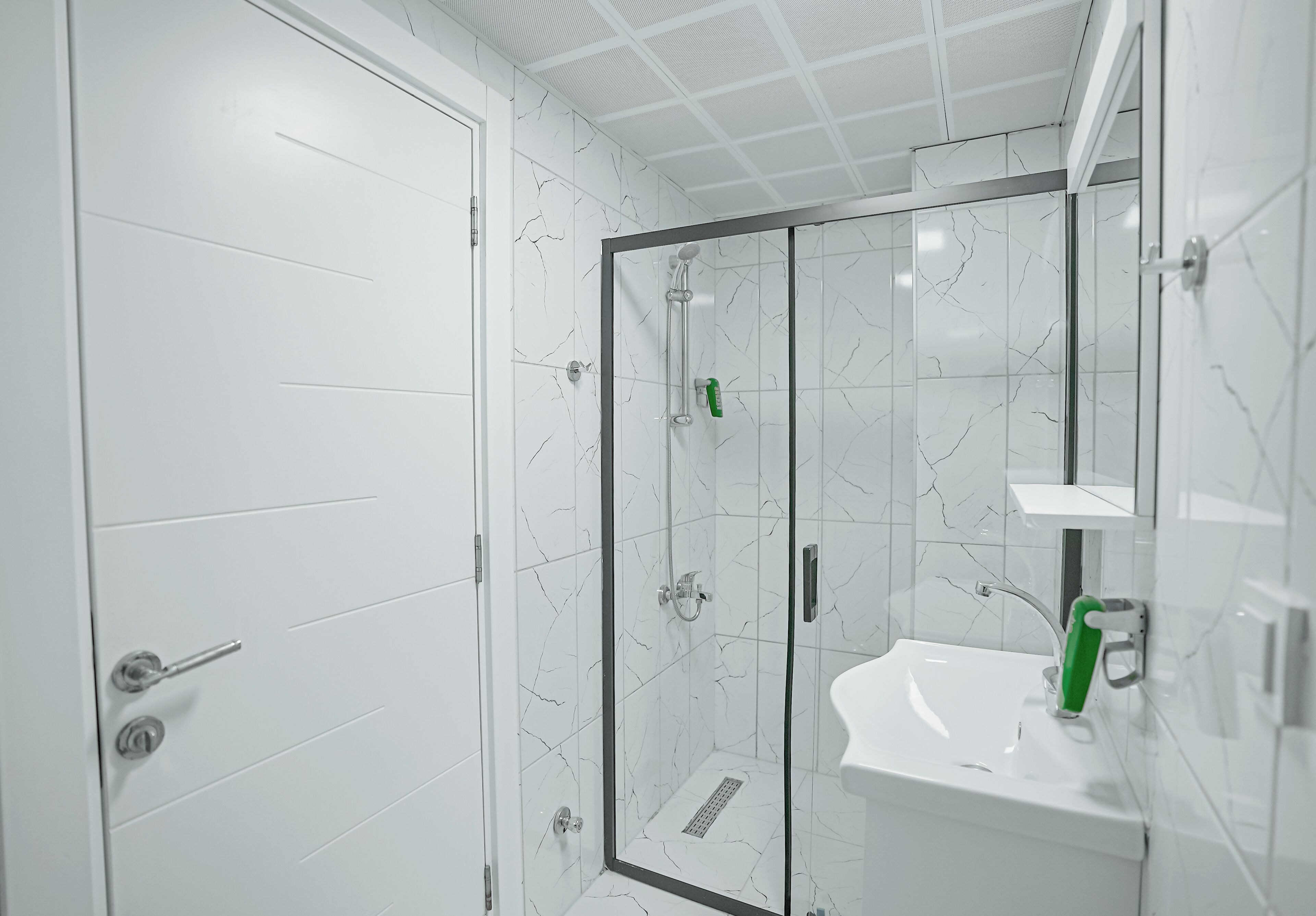 Un baño con ducha de vidrio, un lavabo blanco y un espejo.