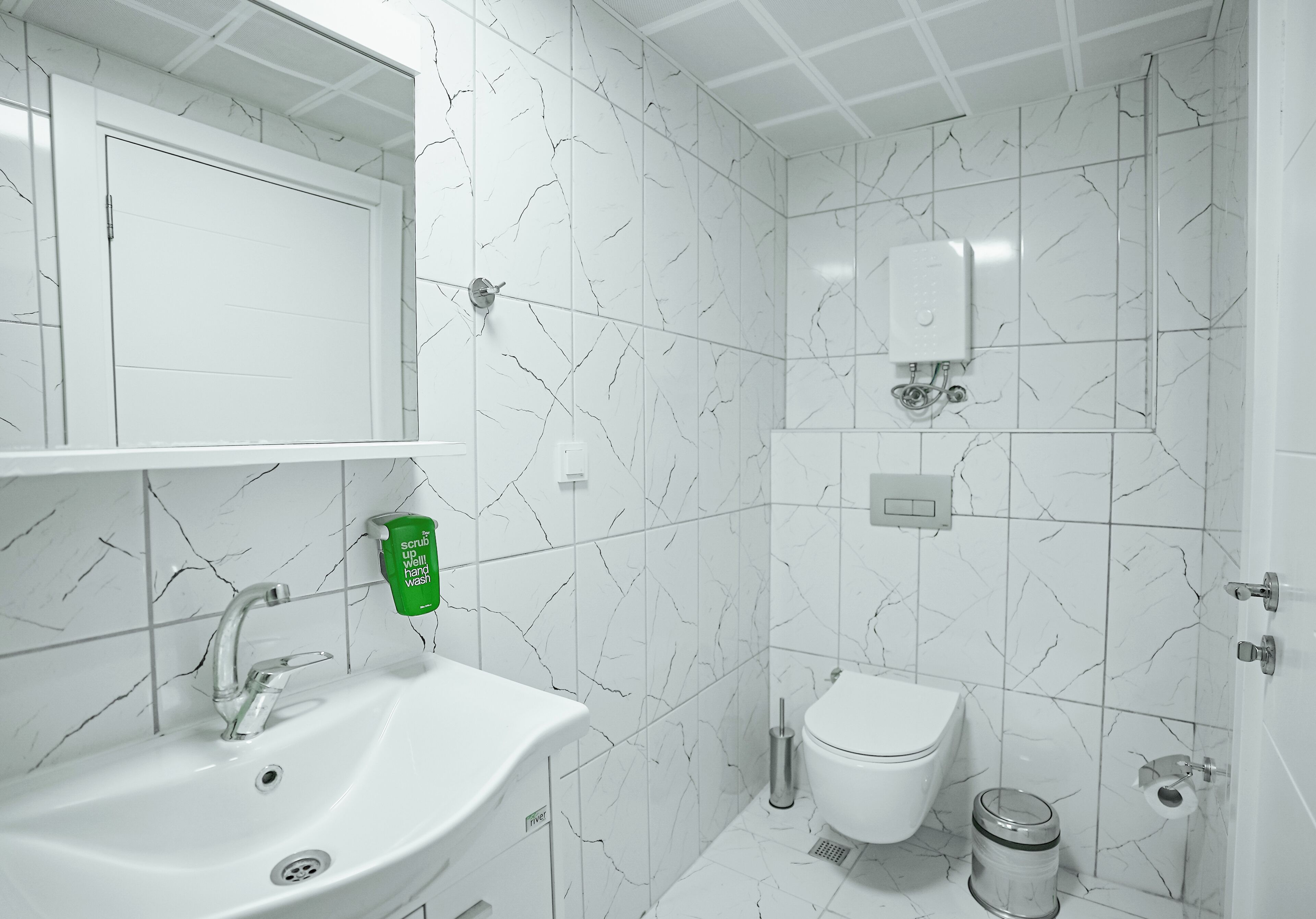 Un baño con lavamanos, inodoro y ducha blancos.