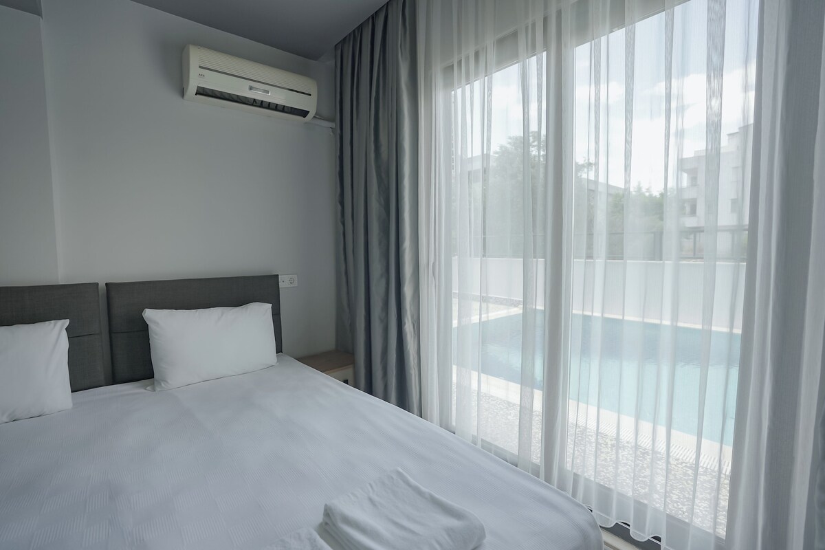 Een hotelkamer met een bed, een airconditioning en uitzicht op een zwembad.