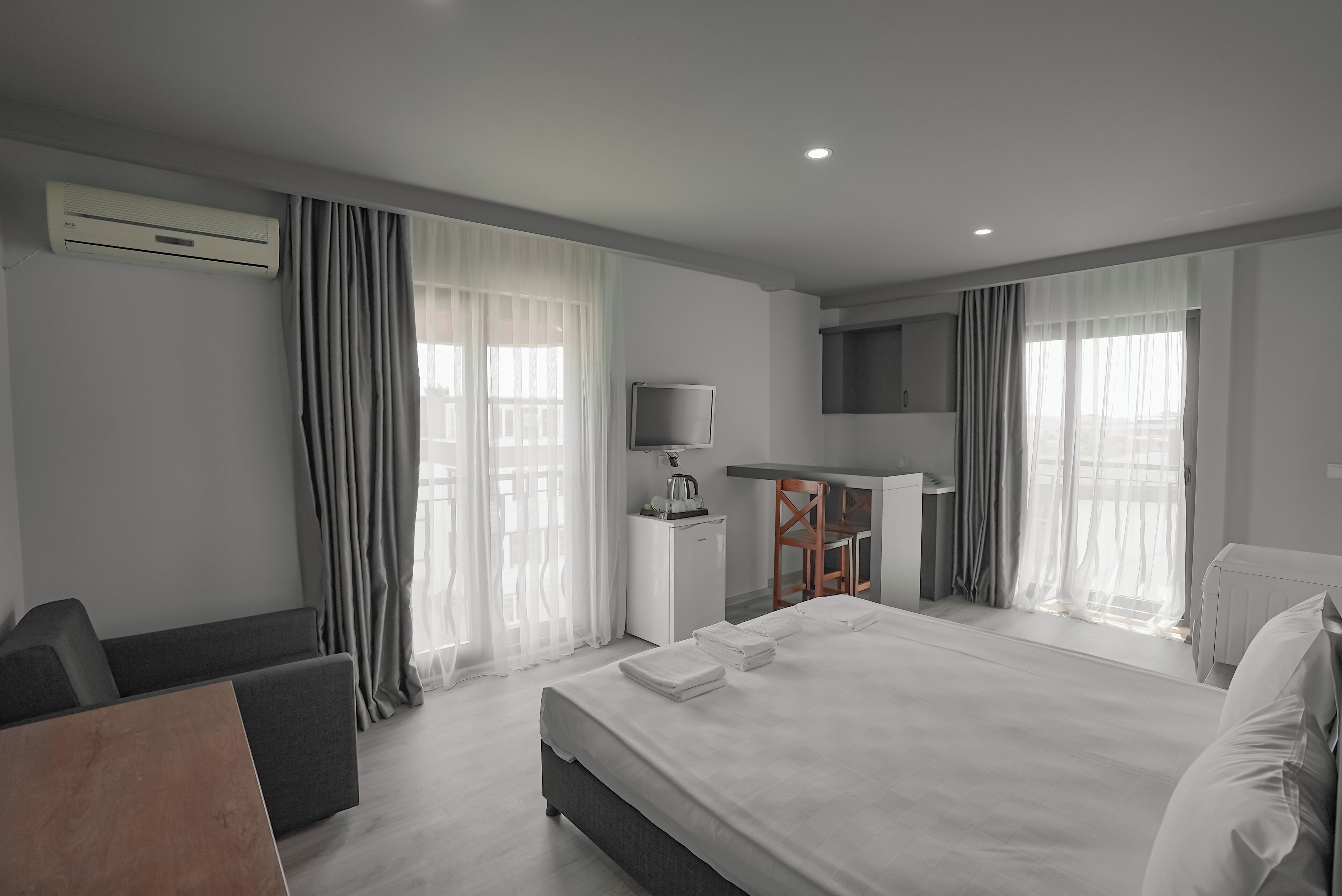 A modern hotel room with a large bed, a desk, a TV, and a view of the city.
