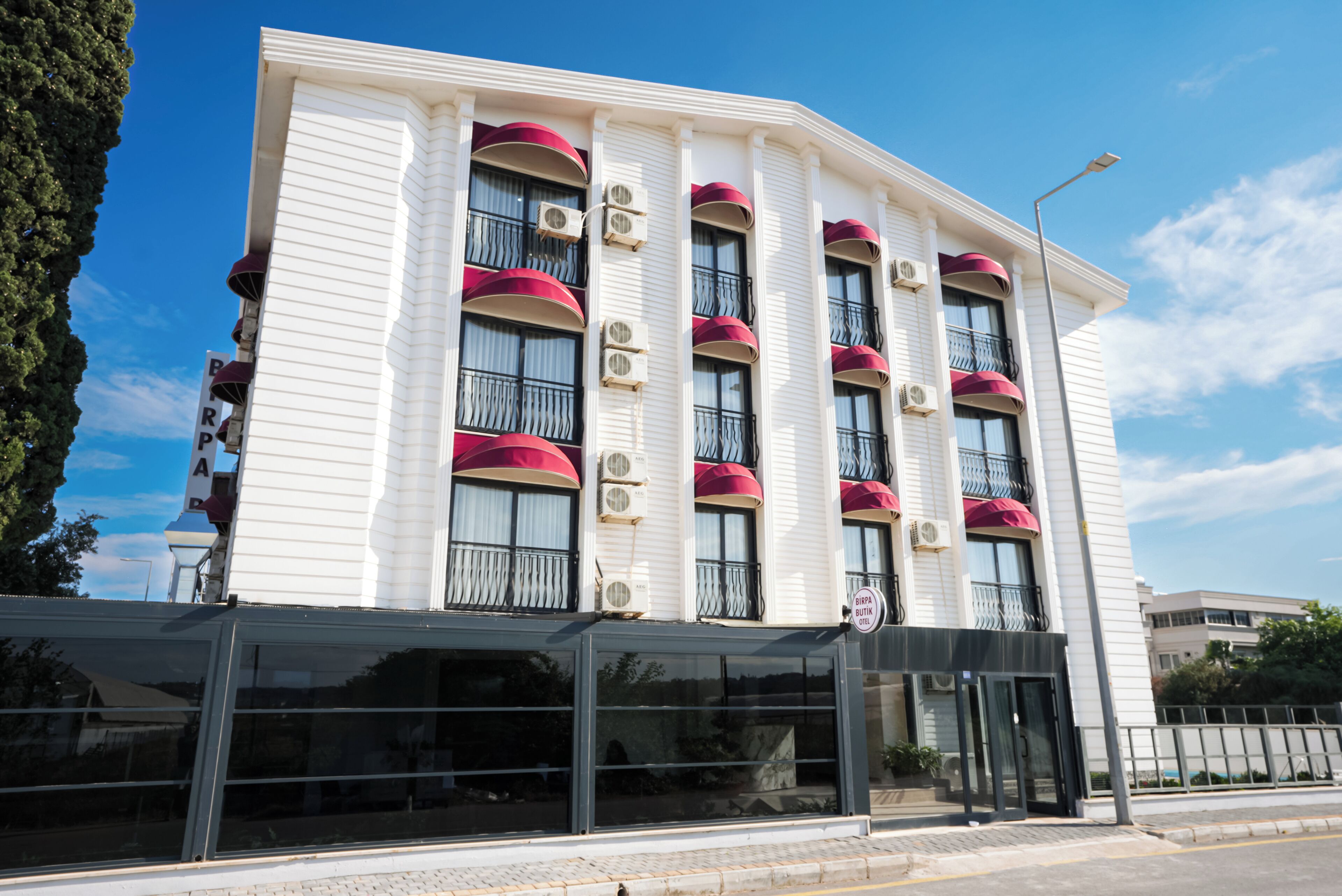A multi-story hotel with balconies, air conditioning units, and a glass entrance.