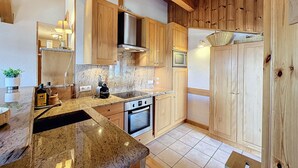 A kitchen with wooden cabinets, a granite countertop, a stainless steel oven, and a microwave. - Modern Apartment with Mountain Views, Near Combloux Center (Combloux)