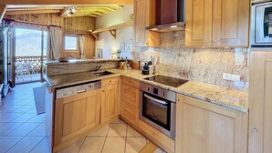 A kitchen with wooden cabinets, a built-in oven, and a dishwasher. - Modern Apartment with Mountain Views, Near Combloux Center (Combloux)