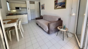 A compact living space with a kitchenette, a dining area, a sofa, and a small table.