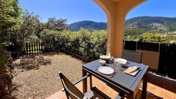 A patio table set for dining with a view of mountains and a village.