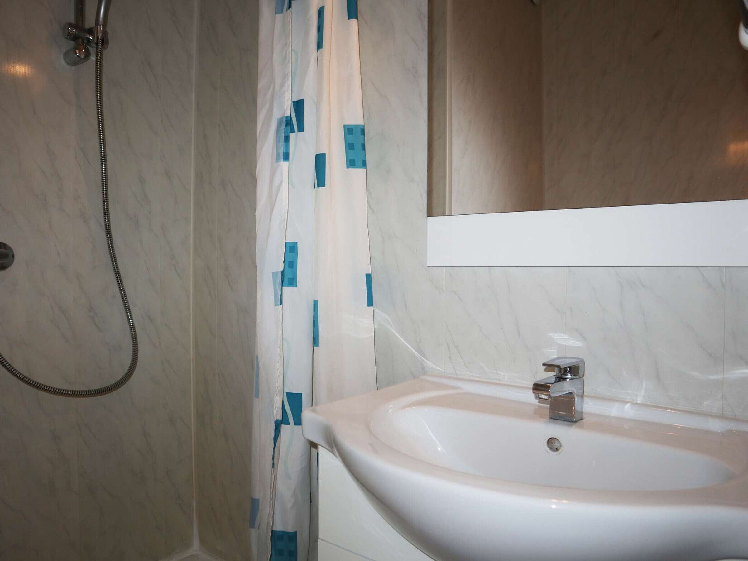 Ein Badezimmer mit Dusche, Waschbecken und Spiegel.