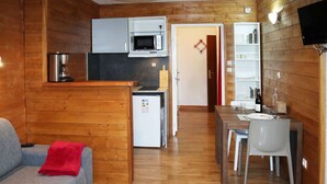 A compact living space with a kitchenette, a dining area, and a seating area with a red throw blanket. - Cozy studio for 2 in the heart of Les Orres 1650 (Les Orres)