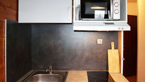 A compact kitchen with a sink, a microwave, and a built-in stovetop. - Cozy studio for 2 in the heart of Les Orres 1650 (Les Orres)