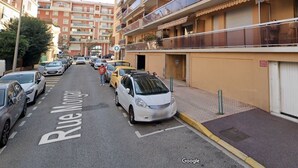 Una calle con coches aparcados y un edificio con balcones.