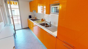 Una cocina moderna con gabinetes naranja, un lavamanos doble y un microondas.