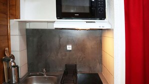 A compact kitchen with a microwave, a sink, and a stovetop.