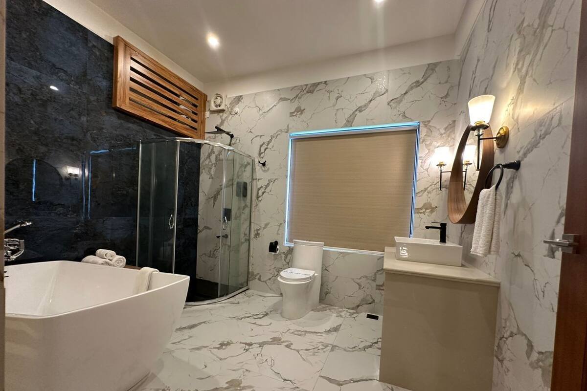 Une salle de bain comprenant une baignoire sur pieds, une douche à parois de verre, des toilettes et un meuble-lavabo avec un miroir.