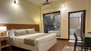 A bedroom with a bed, bedside table, lamp, and a view of a bathroom and hallway. - Legphel Hotel (Phuntsholing)
