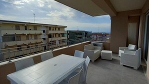 En balkon med et hvidt bord og stole, en sofa og en lille hvid lænestol.