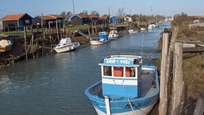 Een smalle waterweg met aanmerende boten, houten huizen met rode daken, en een houten hek.