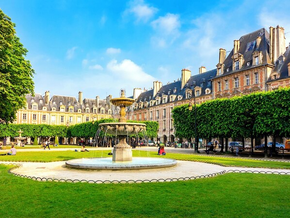 A historic building with a central fountain, surrounded by well-maintained lawns and trees.
