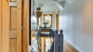 A spacious hallway with wooden doors, a balcony with a railing, and a large window allowing natural light. - Victorian Lake Oasis (Lake Huntington)