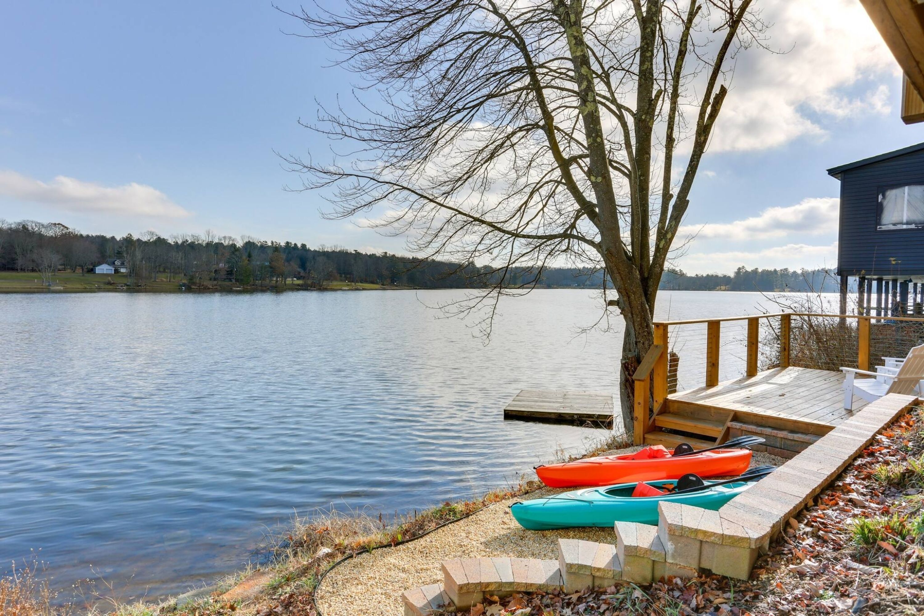 A lakeside dock with kayaks and a wooden deck.